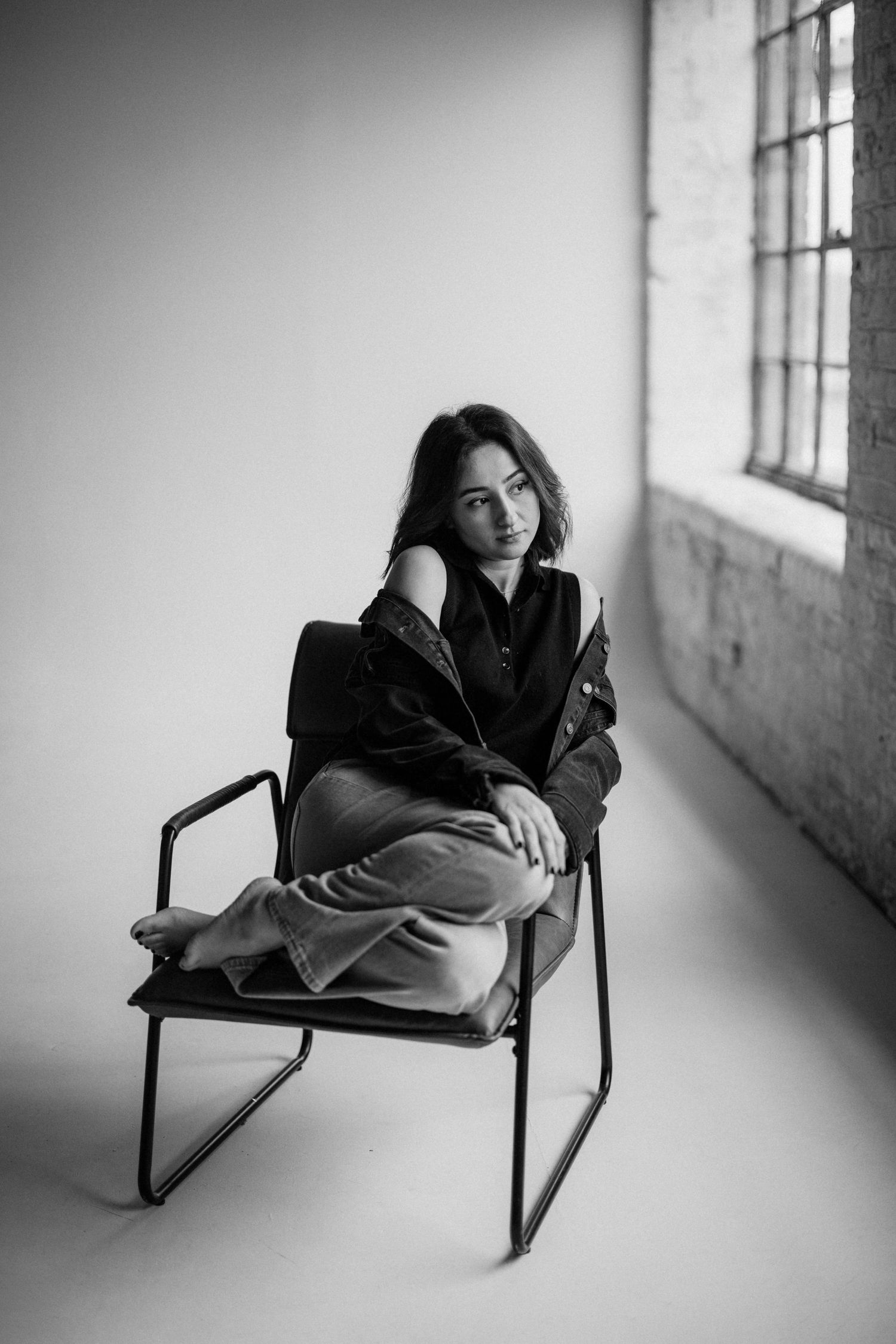 A series of moody portraits showing someone sitting on a black wooden chair against a minimalist dark background.