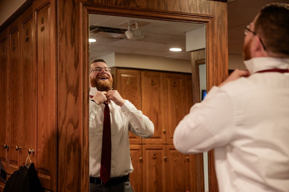 Person in white shirt standing in front of wooden paneled walls while holding a phone to their ear.