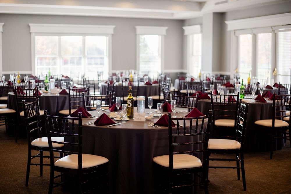Elegant banquet hall with burgundy tablecloths and cream chairs set up for a formal dining event.