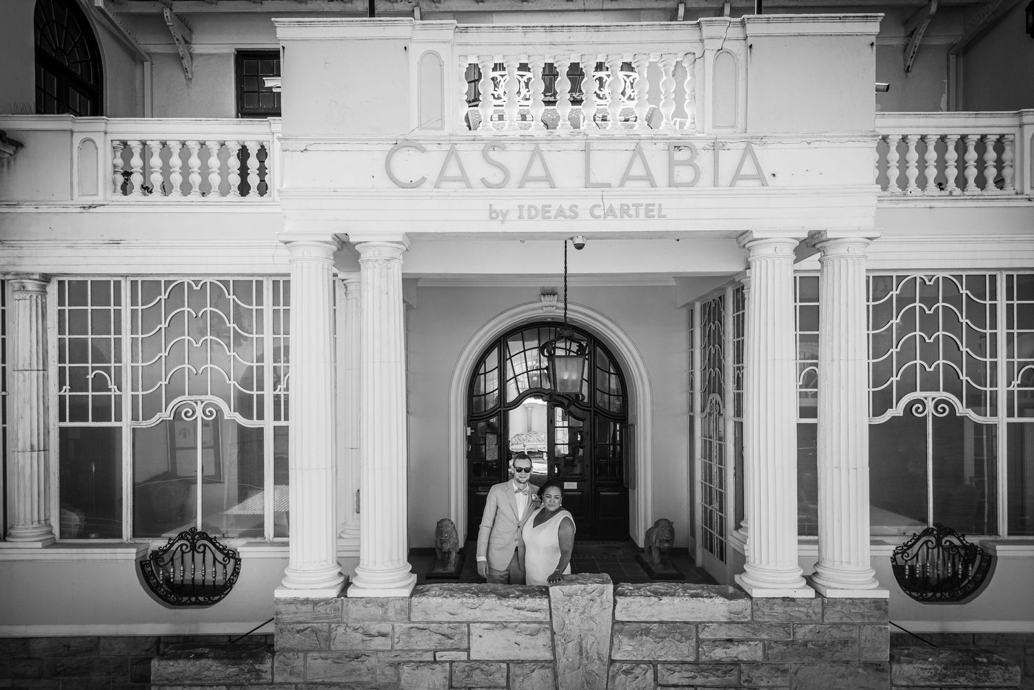 Couple embracing in the arched entrance of Casa Labia by Ideas Cartel in a black and white wedding photo.