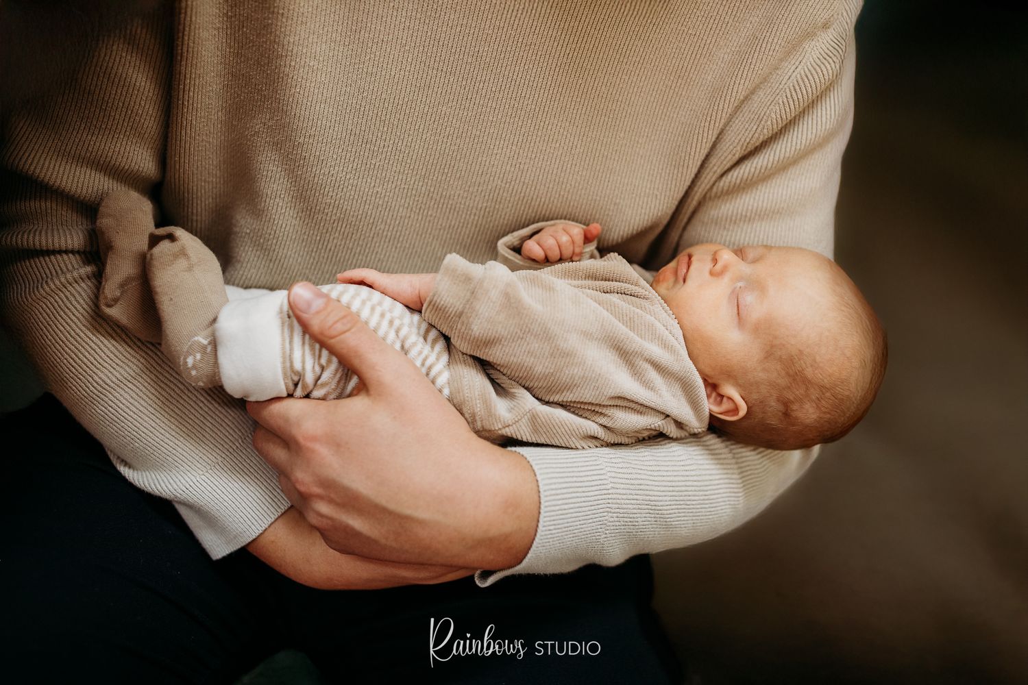 Een newborn slapend in de armen van zijn papa.