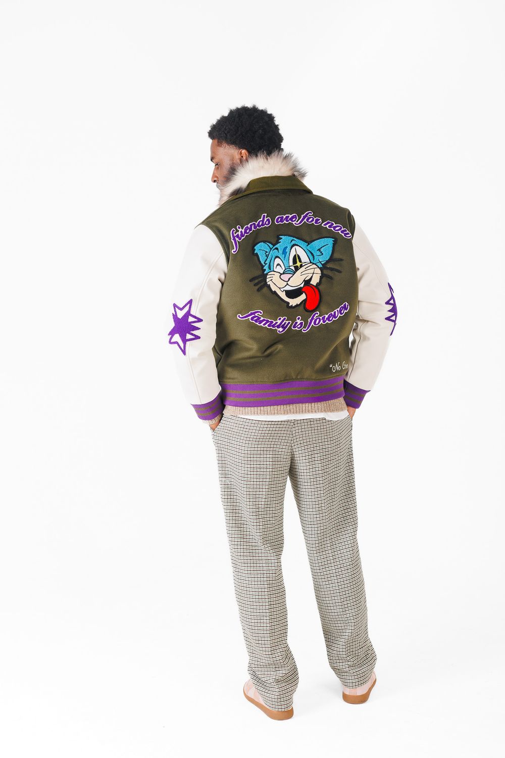 Cartoon character embroidered on olive green jacket with checkered pants shown from three different back angles.