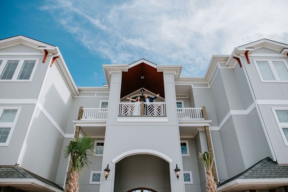 White coastal wedding venue exterior with multiple levels and architectural details against blue sky.