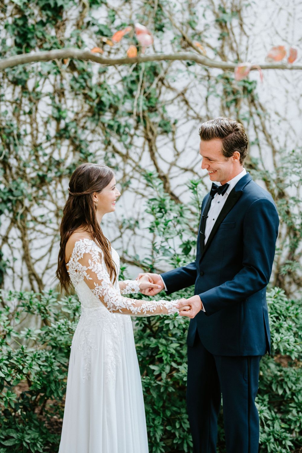 First look moment between couple in garden setting with ivy covered walls.