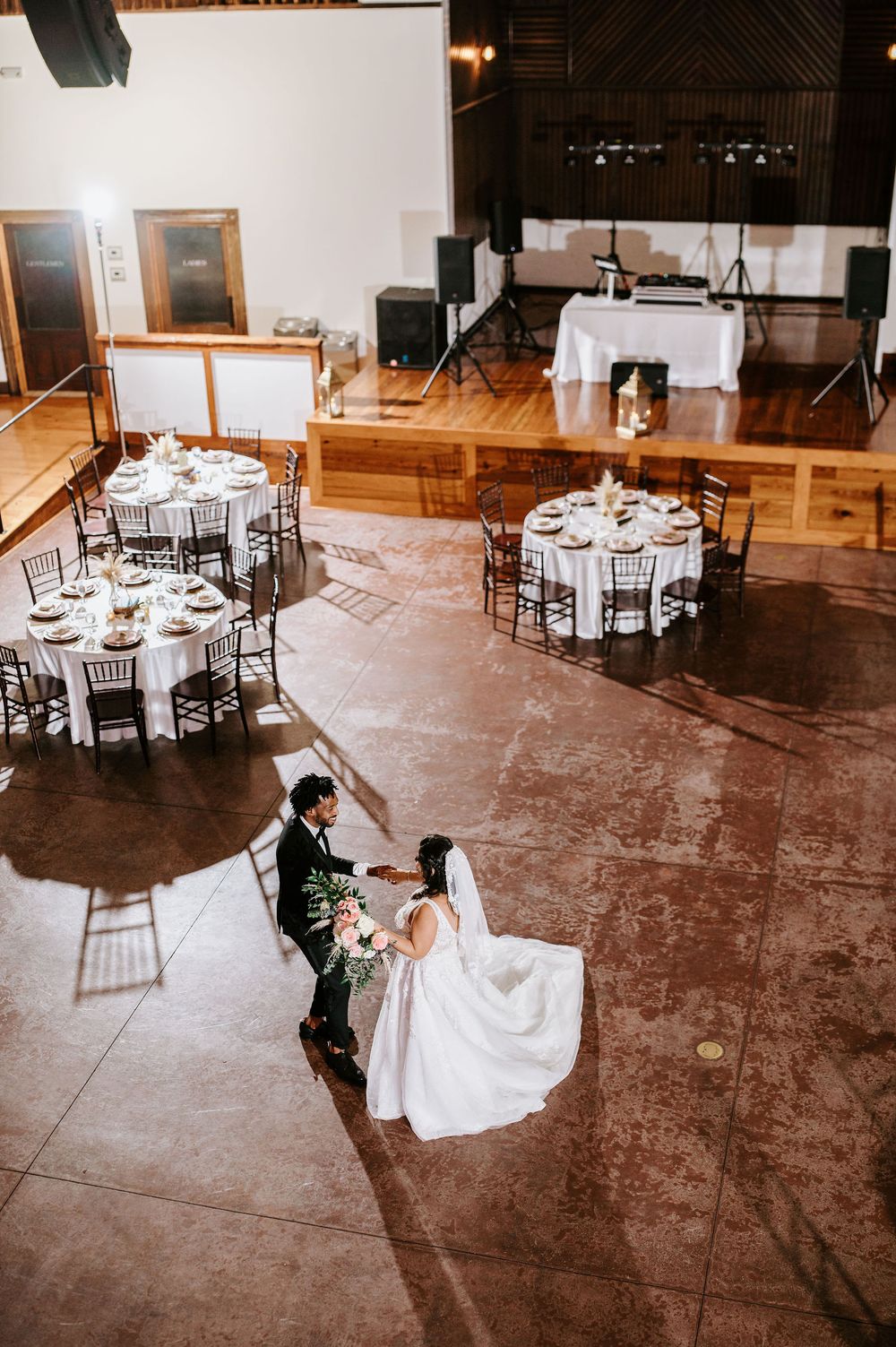 Reception venue with round tables and chairs set up on a polished concrete floor.