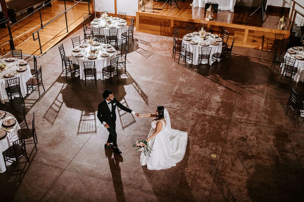 Overhead view of a wedding reception venue with elegant round tables and chairs set up on a polished concrete floor.
