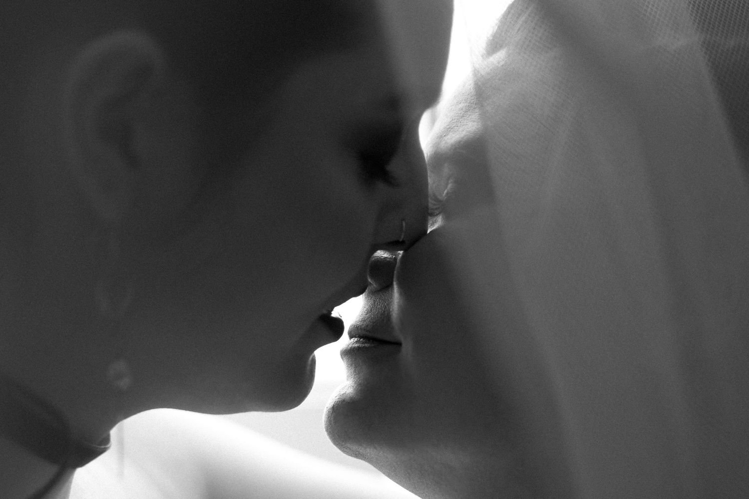 Black and white photo of an LGBTQ couple kissing in a romantic close-up moment.