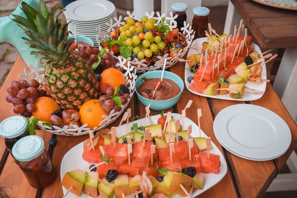 Elegant display of fresh fruit platters with watermelon, pineapple, and grapes arranged on white serving dishes.