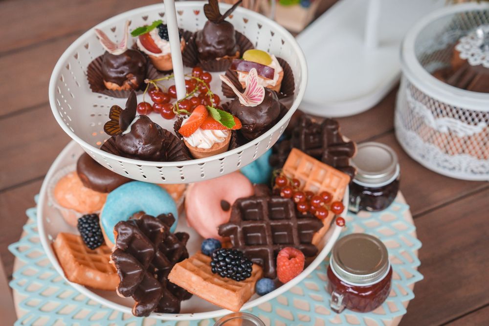 A tiered dessert display with chocolate treats, colorful macarons, and sweet confections arranged on decorative plates.