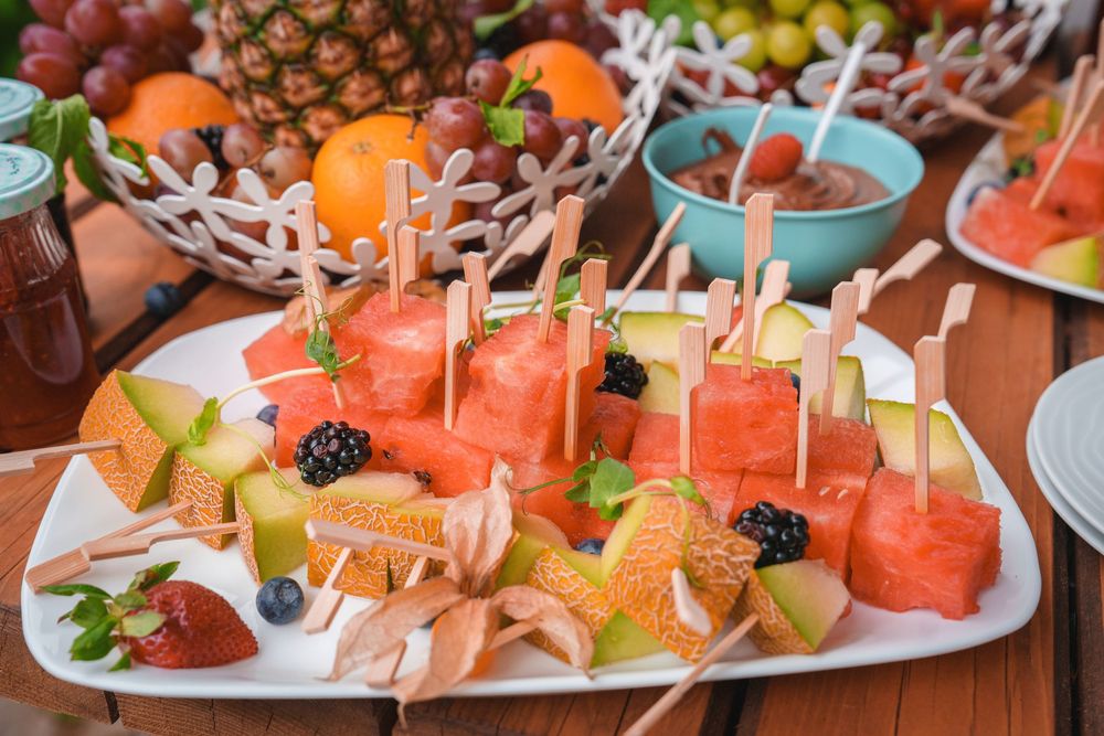 Colorful fruit platter featuring watermelon, pineapple and berries with decorative toothpicks for serving.