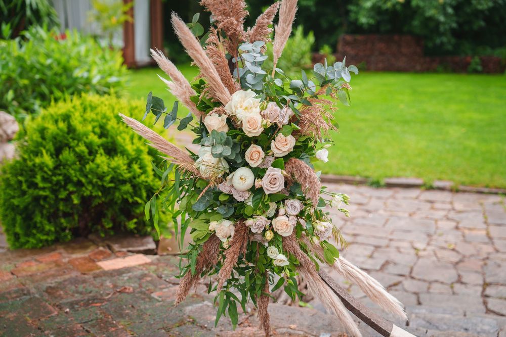 A curved stone garden path lined with lush greenery and pink floral arrangements leads through a vibrant landscape.