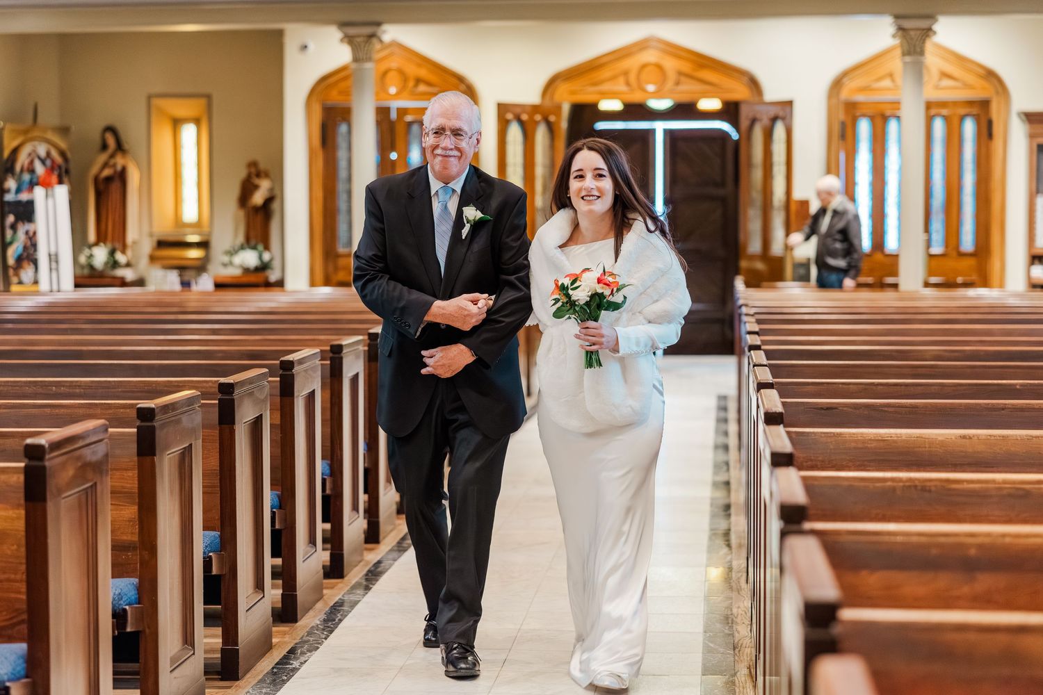A bride walks down the church aisle with someone by her side during a traditional wedding ceremony.