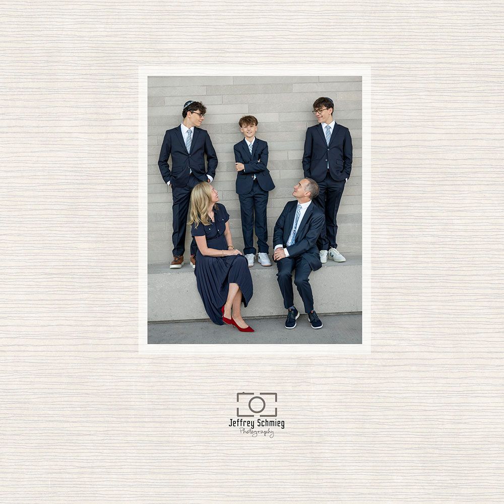 Group of people in navy suits sitting and standing against white wall in casual business setting.