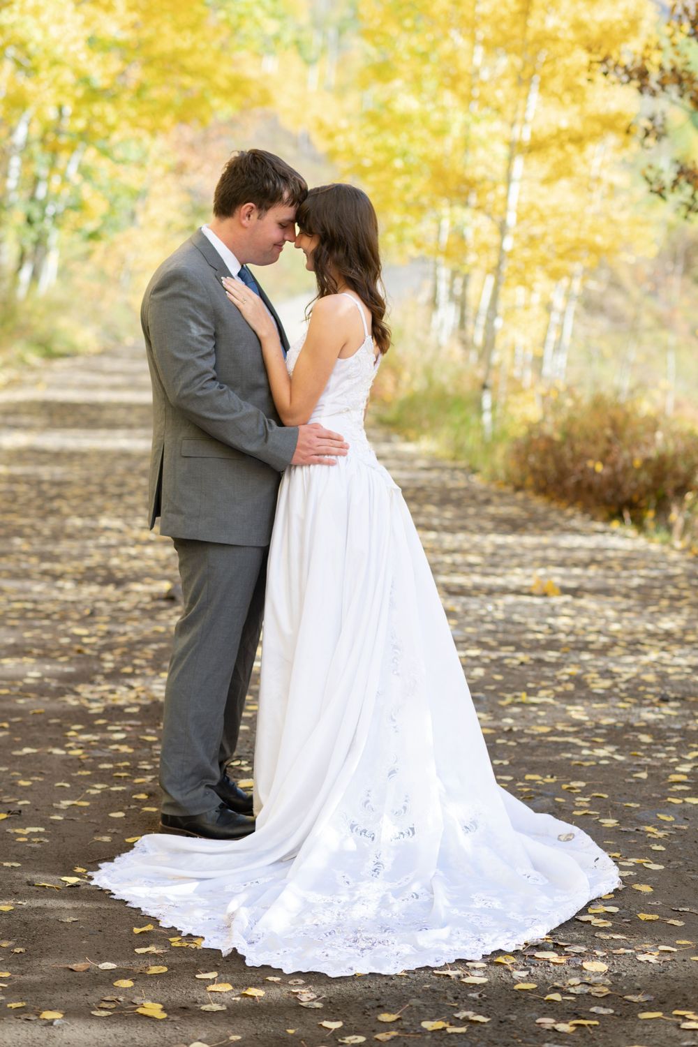 Bride and groom share a romantic forehead touch outdoors in autumn, surrounded by golden foliage in the mountains near Ridgway.