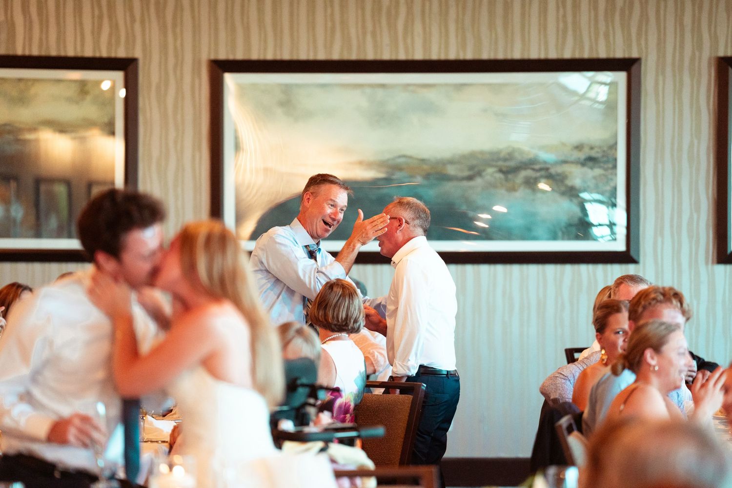 Wedding party dances and celebrates together in a white tent reception venue during a joyful celebration.