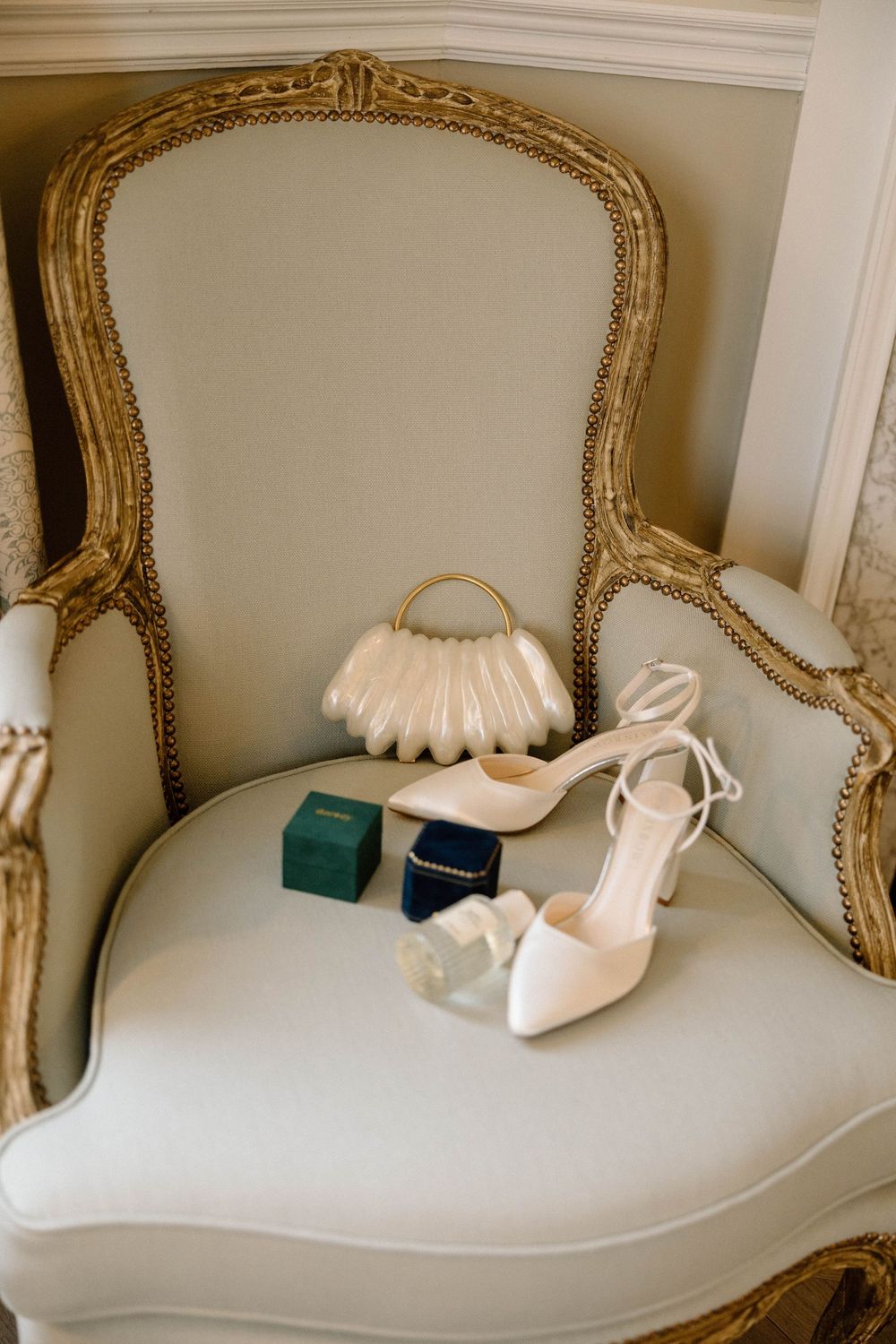 Elegant white bridal shoes displayed on ornate gold-framed chaise lounge.