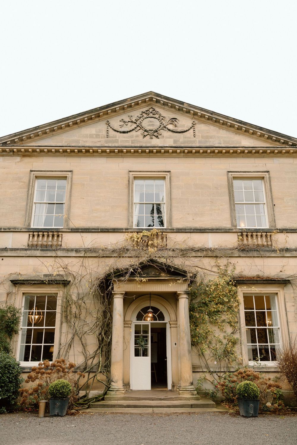 Stately Georgian-style mansion with symmetrical windows and ornate architectural details in beige stone.