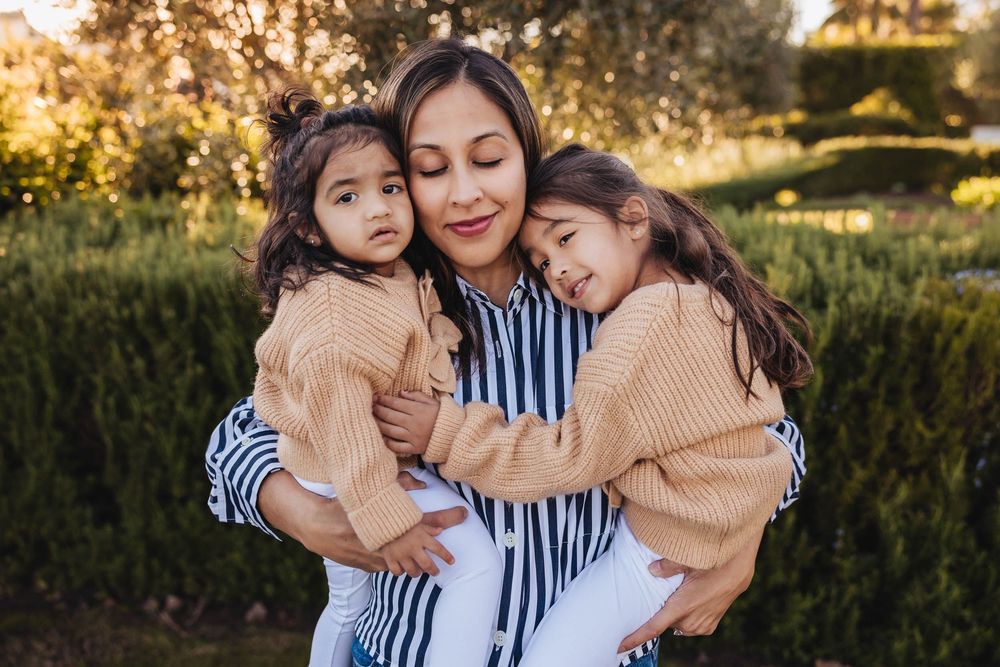 A tender family moment captured at golden hour in a garden with warm autumn tones and natural lighting.
