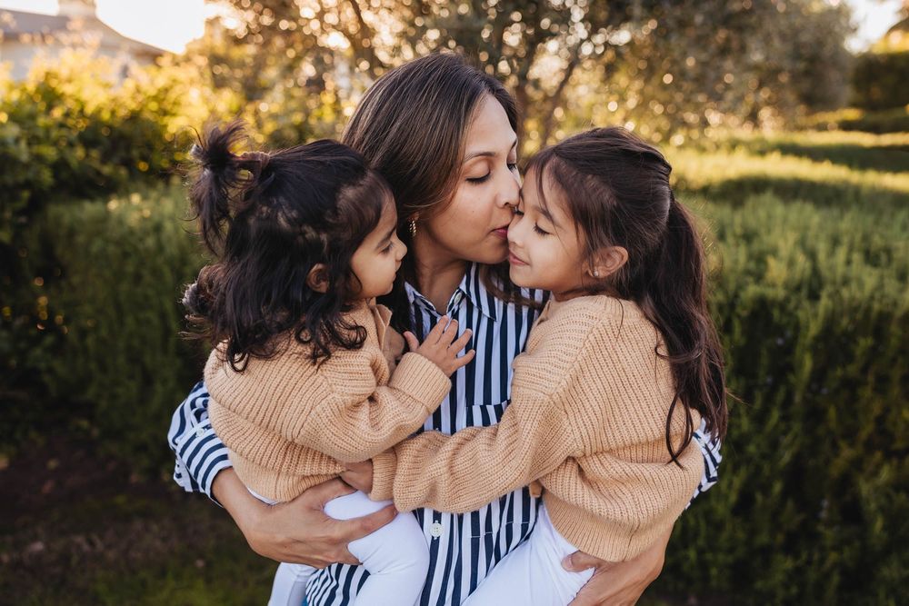 A loving family shares tender moments together in a sun-drenched garden setting at golden hour.
