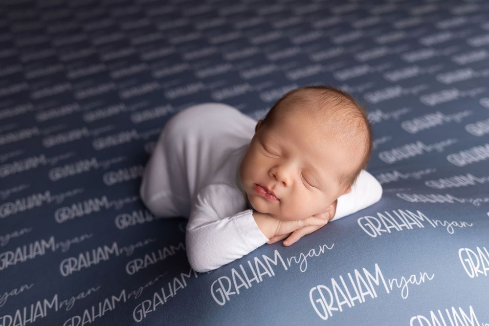 Newborn baby on name-stamped blanket, taken by Jen Knightstep, Photographer