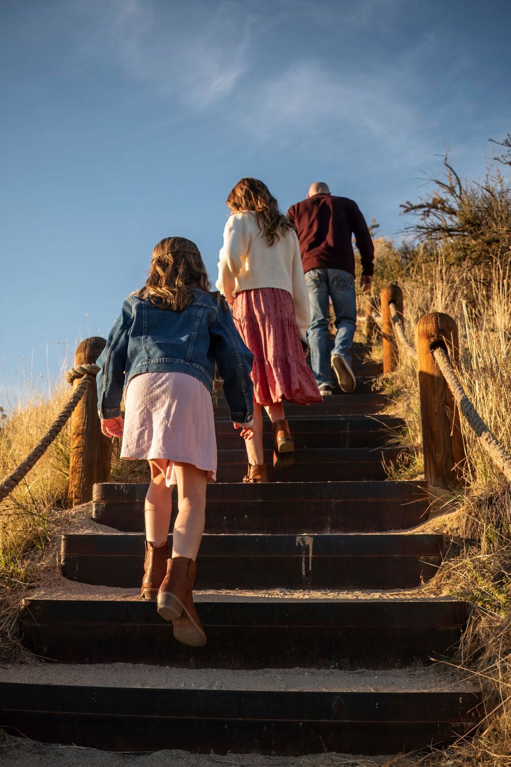 Group climbing wooden stairs on a hillside trail during golden hour sunset.