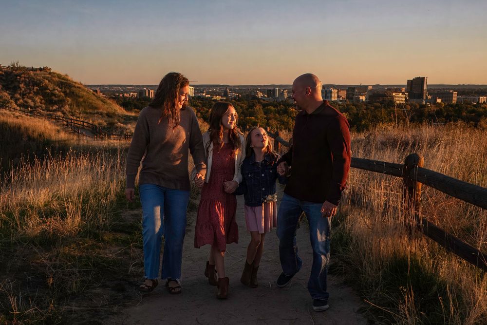 Group of people walking along a scenic foothill path during golden hour sunset.
