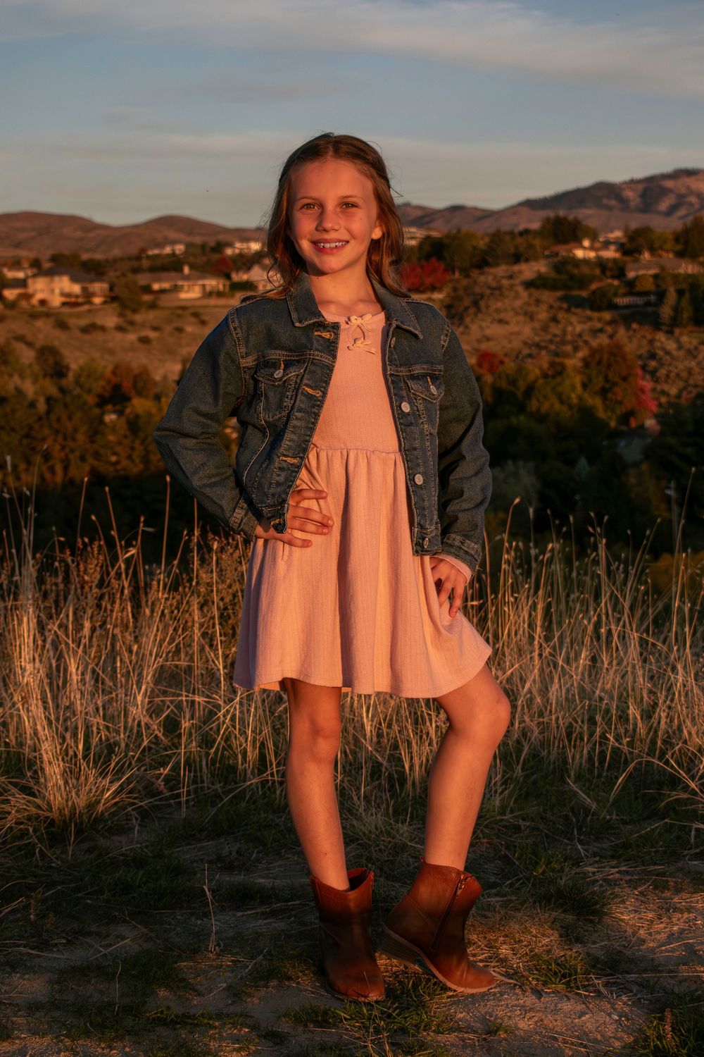 A portrait in a desert landscape with mountains and dry brush in the background.