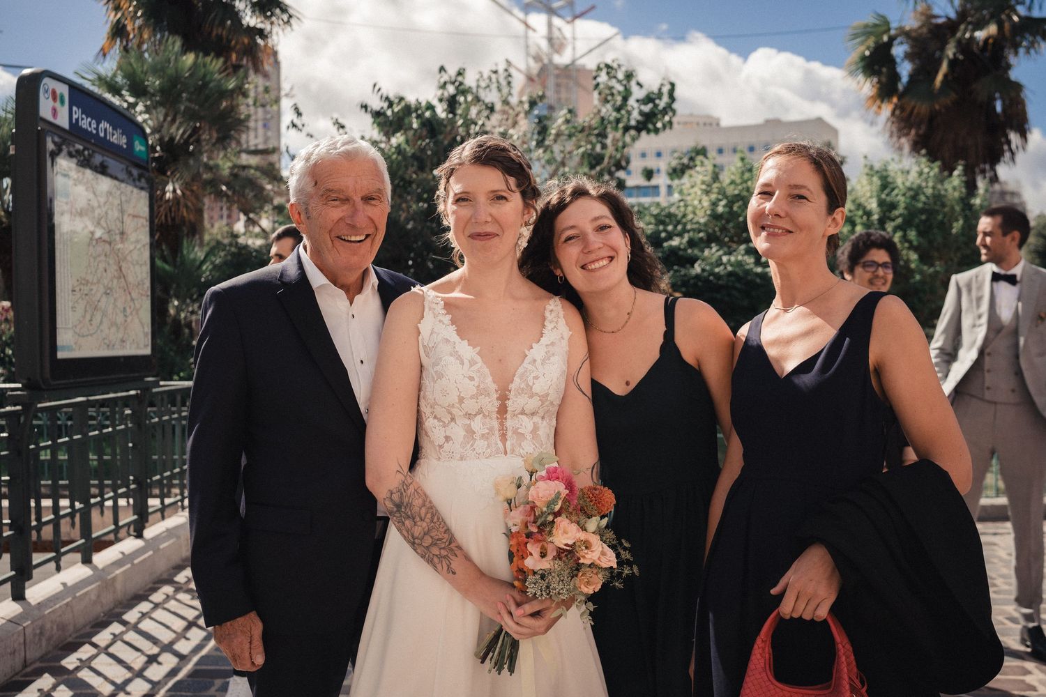 Outdoor wedding ceremony with guests gathered under palm trees and cloudy skies.