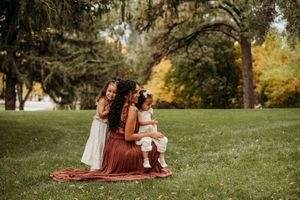 Family enjoying a picnic together on a grassy hill during a warm autumn day.