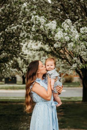 A tender outdoor spring moment captured under blooming white cherry blossom trees in a garden setting.