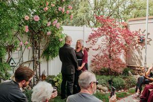 A group gathers in a lush garden setting with blooming flowers and greenery for an outdoor celebration.
