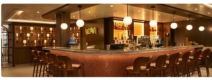 Modern hotel bar interior with red bar stools and warm lighting creates an inviting atmosphere for guests.