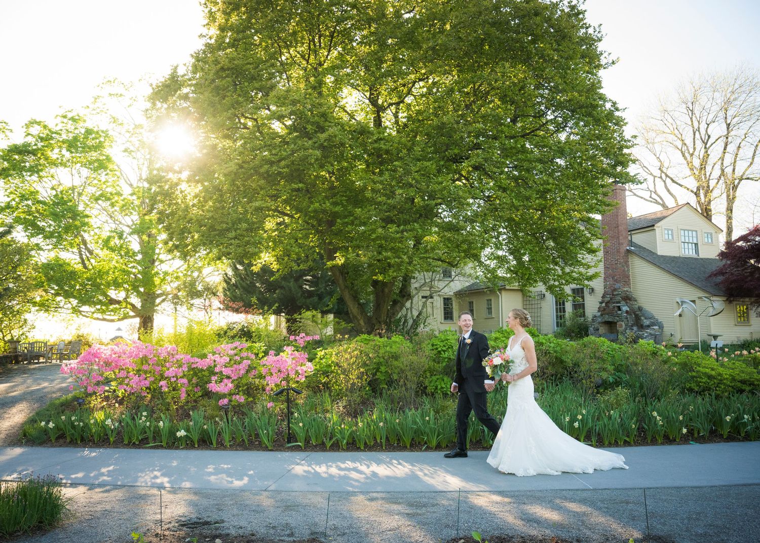 A romantic autumn wedding photo under a wooden pergola as a flowing white veil catches the breeze.