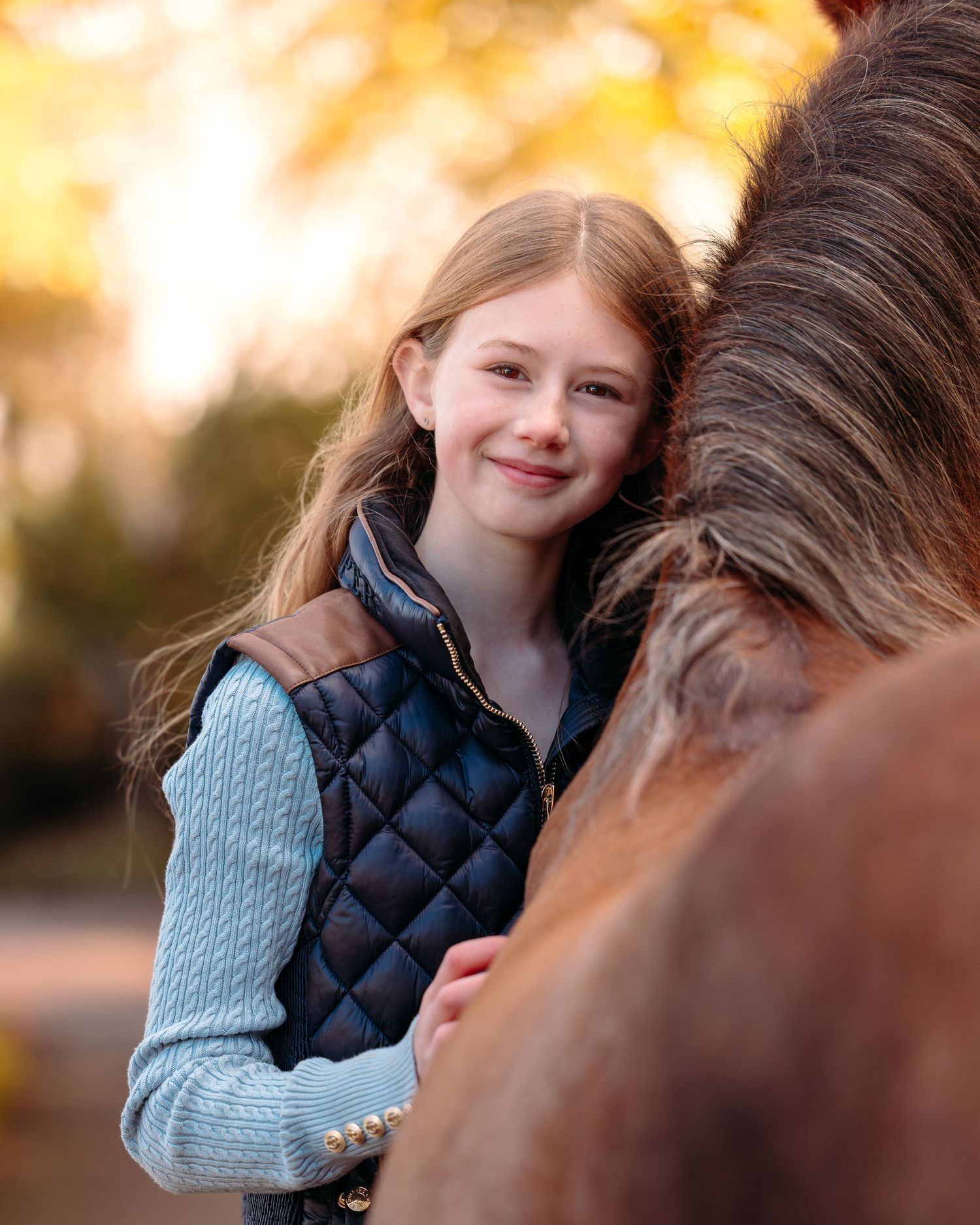 A heartwarming autumn portrait showing a close bond between a rider and their horse in soft golden light.