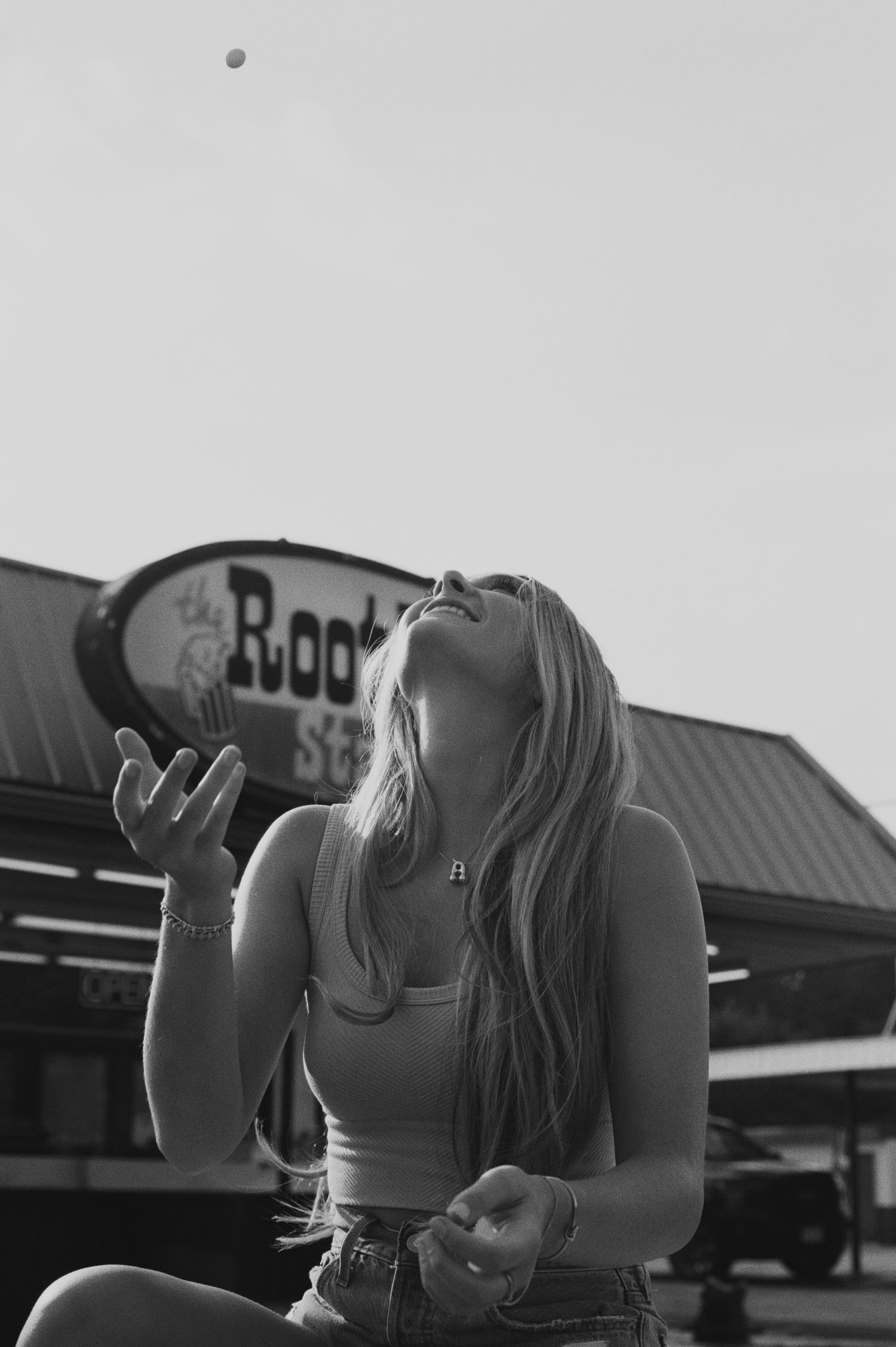 A black and white photo showing a person throwing a candy up in the air, trying to catch it in their mouth.