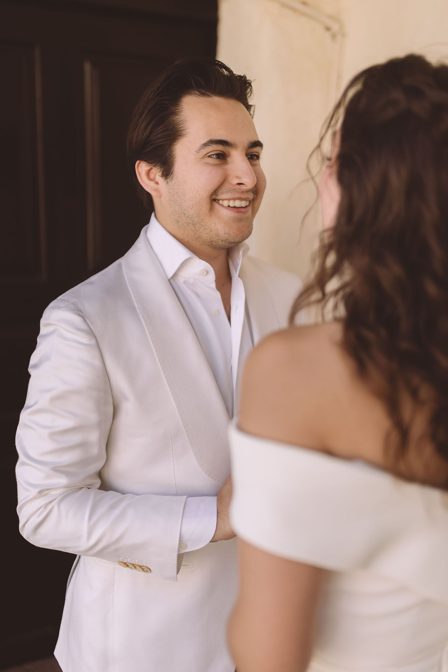 A groom smiles warmly at his bride at their Santorini wedding.