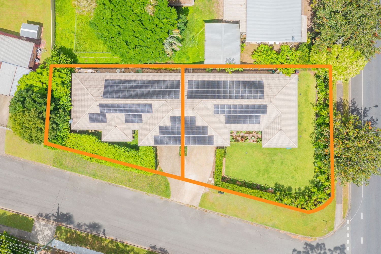 Aerial view of a property with solar panels on the roof, outlined in orange, beside a quiet suburban road.