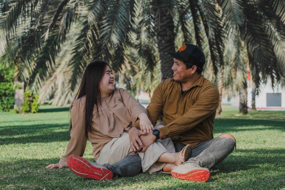 Couple sitting in Abu Dhabi park, palm trees background. Lifestyle Family & Couple Photographer in Abu Dhabi.