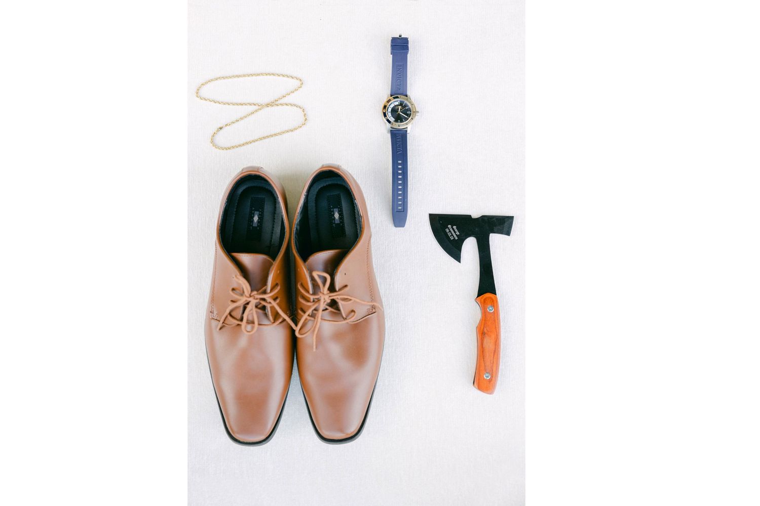 Flatlay of brown leather shoes and boots arranged in a row with orange and blue accents.