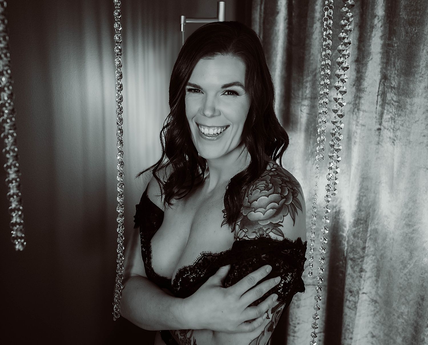 brunette woman stands under hanging crystals in black lace top by Wisconsin boudoir photographer
