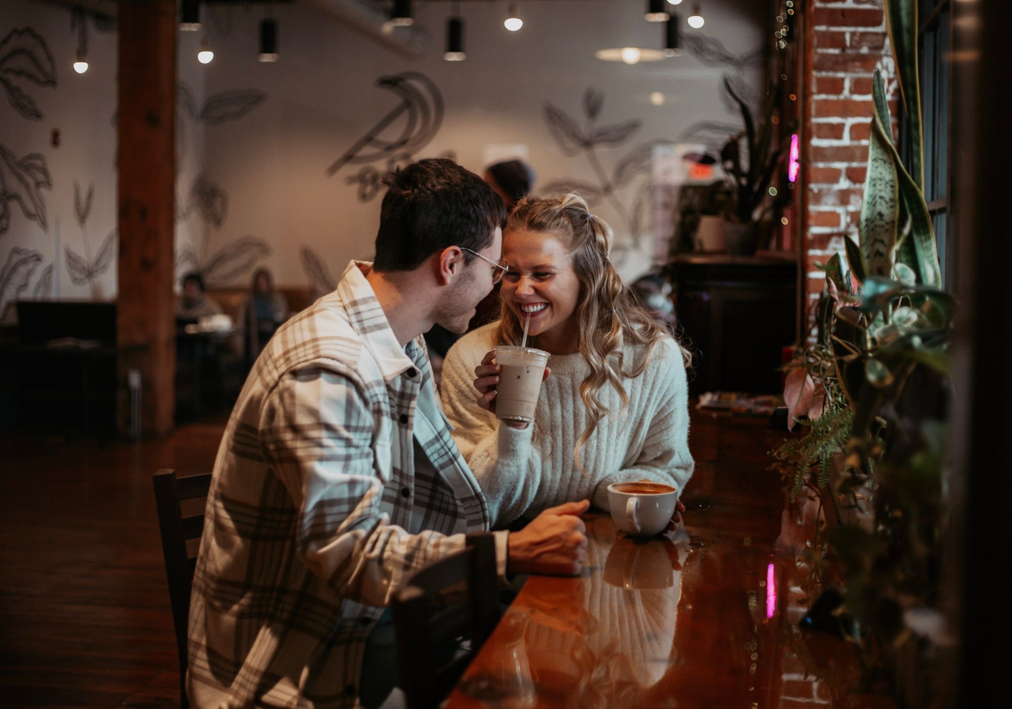 Couple sharing a romantic moment laughing together at a coffee shop bar counter.
