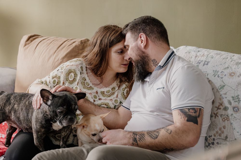 A couple relaxes on a couch with their cat in a series of intimate lifestyle photos.