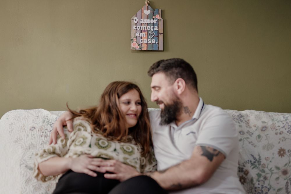 A couple relaxes on a floral couch with their small dog in a cozy living room setting.