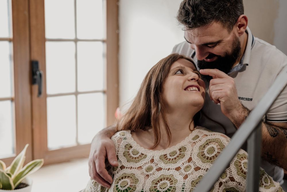Romantic couple in a white dress and suit share intimate moments in a rustic indoor setting with natural light.