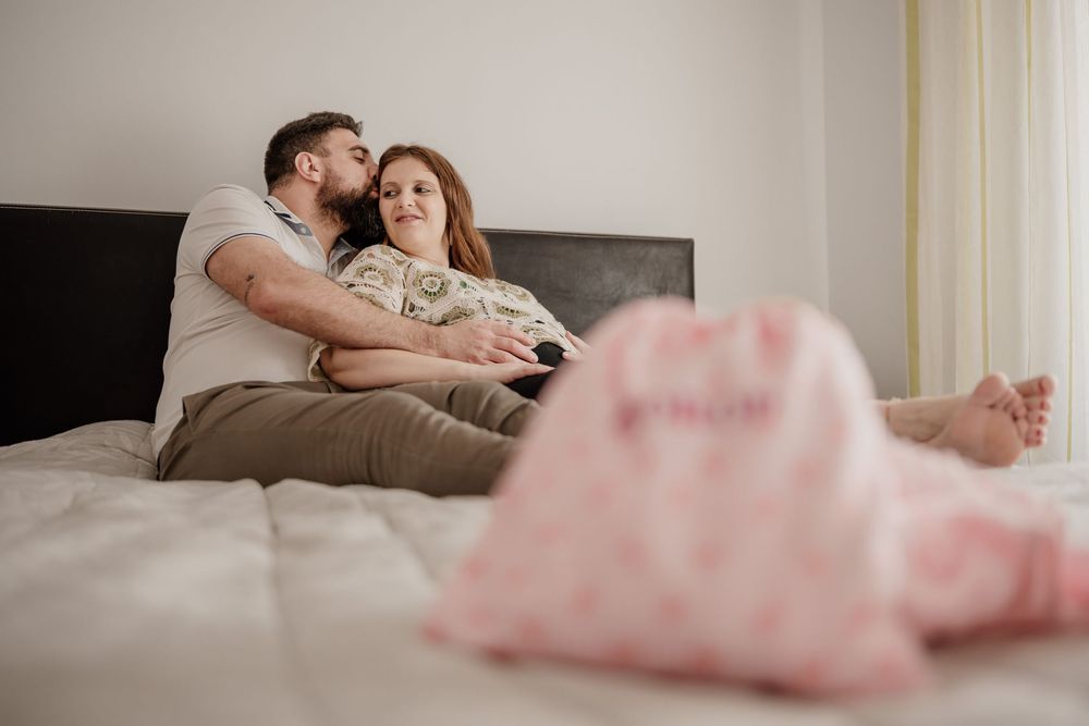 Couple relaxing together on a white couch sharing intimate moments in a bright living room.