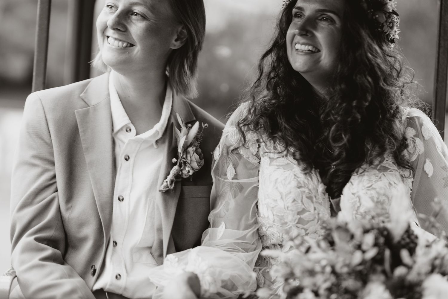 A black and white candid wedding photo showing joyful laughter between the couple during an intimate moment.