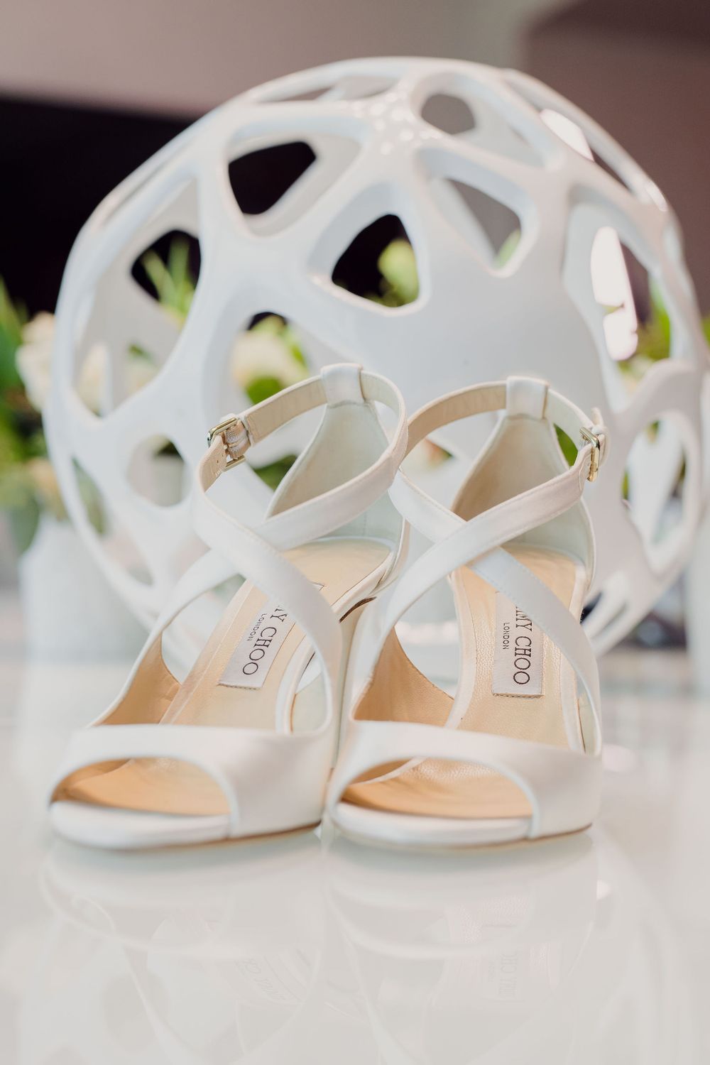 Elegant white bridal shoes with delicate straps and cutout details displayed in a row.