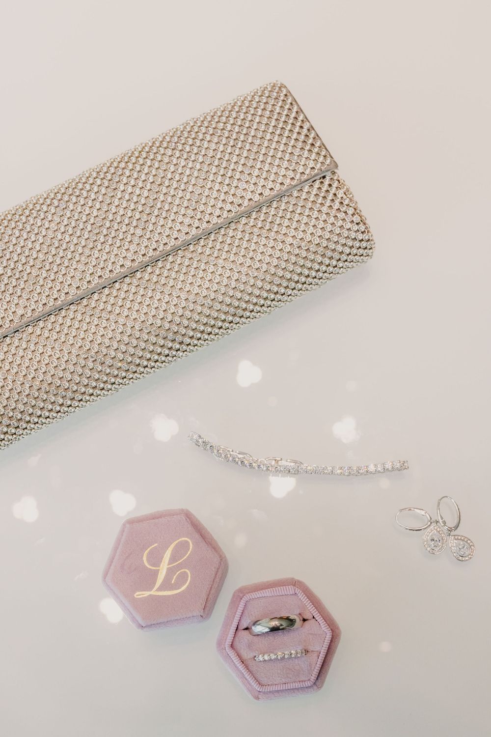 Wedding rings and monogram details on pink hexagonal cards with metallic mesh decor.