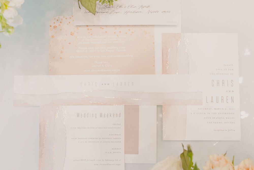 Elegant wedding invitation suite with soft pink and white tones featuring delicate floral elements and calligraphy.