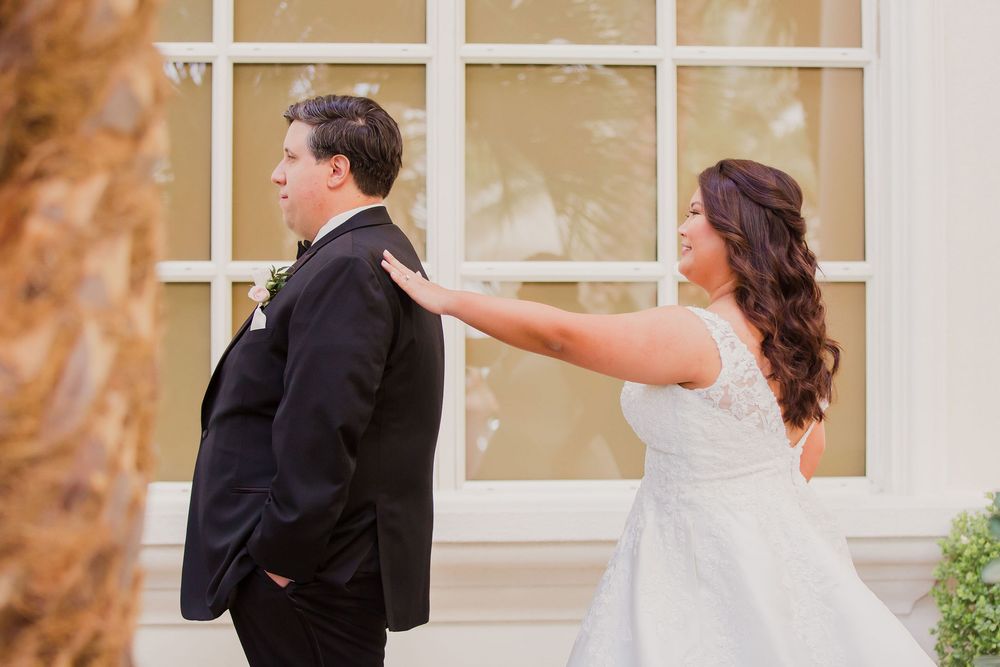 Wedding couple sharing a fun first look moment outside an elegant venue.